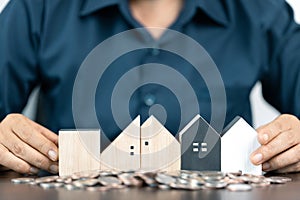 Saving money for house and real estate. Woman hand protecting on stack coins and house model on table