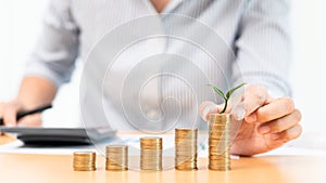 Saving money and investment concept, Business accountant woman stacking coins into increasing columns stack for budget behind desk