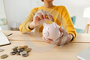 Saving money investment for future. African american girl holding pink piggy bank and putting money coin. Saving