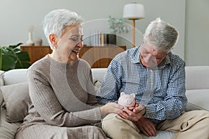 Saving money investment for future. Senior adult mature couple holding piggy bank with money coin. Old man woman