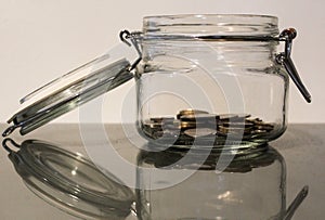 Saving money jar with small pile of coins photo