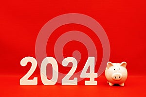 Saving money plan year 2024 for advertising. 2024 wooden word with pink piggy bank on red background studio