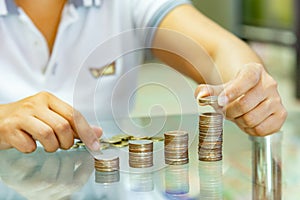 Saving money, woman stacking coins into increasing columns