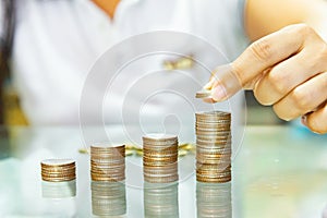 Saving money, woman stacking coins into increasing columns