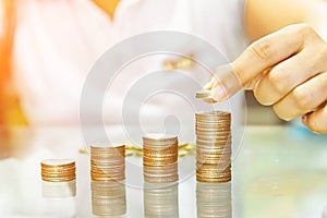 Saving money, woman stacking coins into increasing columns