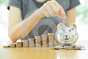 Saving money-young woman putting a coin into a money-box