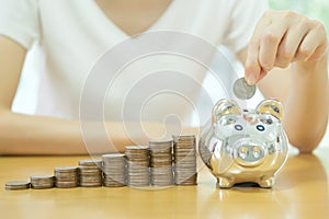 Saving money-young woman putting a coin into a money-box