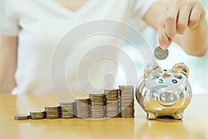 Saving money-young woman putting a coin into a money-box