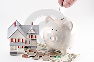 Saving to build / buy a home / house. Piggy bank with coin being