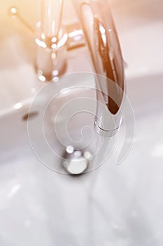 Saving water: Close up of spigot with clear, flowing water. Morning sun