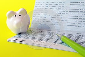 Savings account passbook, piggy bank and pen on yellow background