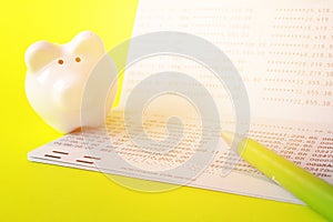 Savings account passbook, piggy bank and pen on yellow background