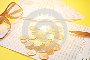 Savings account passbook, Thai money, coins, eye glasses and pen on yellow background