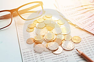 Savings account passbook, Thai money, coins, eye glasses and pencil on blue background