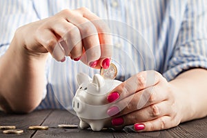 Savings concept,white piggy bank with human female hand inserting  coin inside