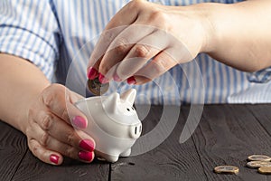 Savings concept,white piggy bank with human female hand inserting  coin inside