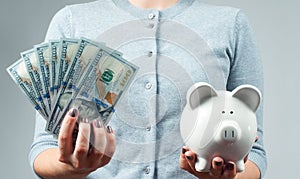 Savings concept. Woman holding piggy bank and bunch of money banknotes.