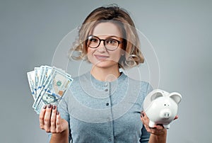 Savings concept. Woman holding piggy bank and bunch of money banknotes.