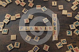 Savings and dealing with money concept. Colorful wooden letters creating the words BUDGET PLANNING. Dark wooden table as