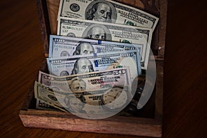 Savings in dollars stored in old wooden box with old clock and s