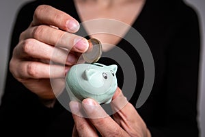 Savings and finance concept. Putting euro coin in small piggy bank