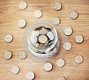 . Savings, investment and a jar full of coins on a wooden table for future financial growth or insurance. Overhead view