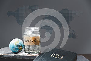 Savings jars full of money and globe with Holy Bible for mission, Mission christian idea. bible and book on wooden table,