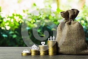 Savings money for the future concepts. Family member, car, house, healthy on stack of coins with money bag on wood table. Depicts