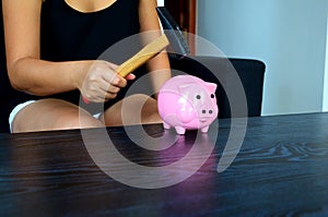 Woman is going to break a piggy bank with a hammer.