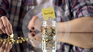 Savings word above glass jar with money, rainy day fund, investment in future