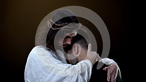 Savior in crown of thrones hugging desperate male, religious peace, forgiveness