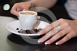 Savoring the Moment: Girl\'s Hand Holding Espresso Coffee Cup in a Cozy Bar