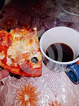 Savoring a slice of pizza with a steaming cup of coffee
