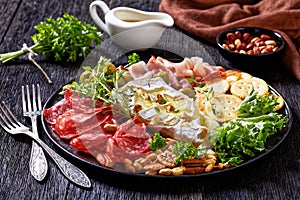 Savory baked brie with crackers, salami, nuts, ham