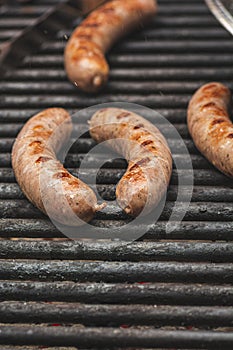 savory brats cooking on an outdoor iron grill