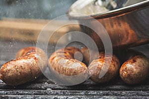 savory brats cooking on an outdoor iron grill