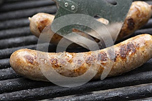 Savory brats cooking on an outdoor iron grill