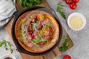 Savory cheese Dutch baby pancake. Dutch Baby pancake with mix tomatoes, parsley and arugula in cast iron pan
