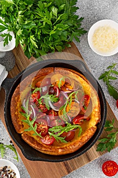 Savory cheese Dutch baby pancake. Dutch Baby pancake with mix tomatoes, parsley and arugula in cast iron pan