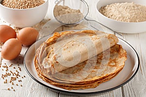 Savory crepes Buckwheat Galettes closeup on a plate with ingredients flour, cereal and eggs closeup on the wooden table.