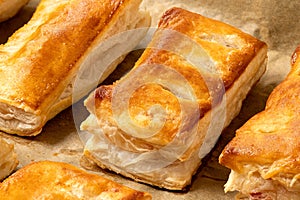 Savory filled puff pastries on baking paper. High angle