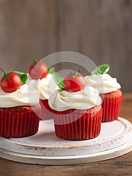 Savory salted tomato cherry cupcakes snacks with cream cheese frosting on on wooden background. Selective focus. Appetizer,