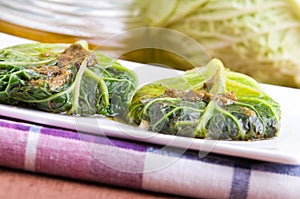 Savoy cabbage rolls on white dish.