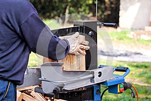 Saw cutting wood for winter. A man cutting firewood for the winter using a modern machine lumber saw.