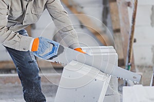 Sawing an autoclaved aerated block with a hand saw at a construction site