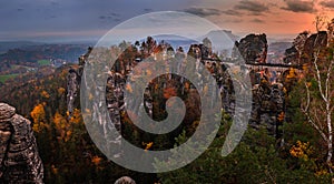 Saxon, Germany - Panoramic view of the Bastei bridge with a sunny autumn sunset with colorful foliage and sky