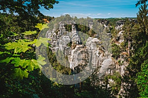 Saxony, Germany. View of famous Bastei rock formation. Elbe Sandstone Mountains. Jutted out rock pillars, pine tree forests down