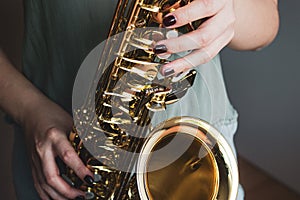 Saxophone girl player hands. Saxophonist playing jazz music. Alto sax musical instrument closeup. Painted nails