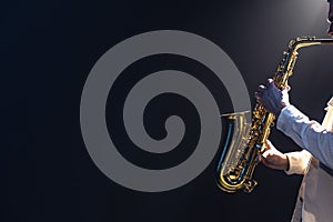 Saxophone in the hands of a man on a dark background, copy space.