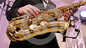 Saxophone player playing a solo in jazz band, performing on lightened stage. Sax musician player with band at concert